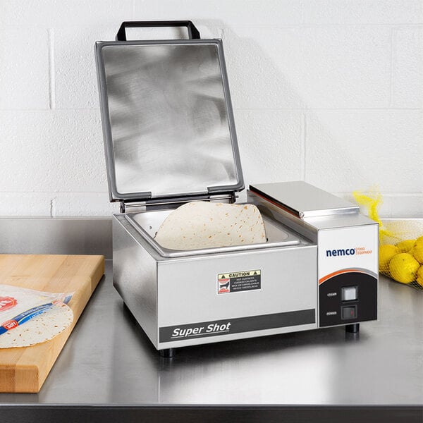 A Nemco Super Shot countertop steamer with an open lid steaming a tortilla.