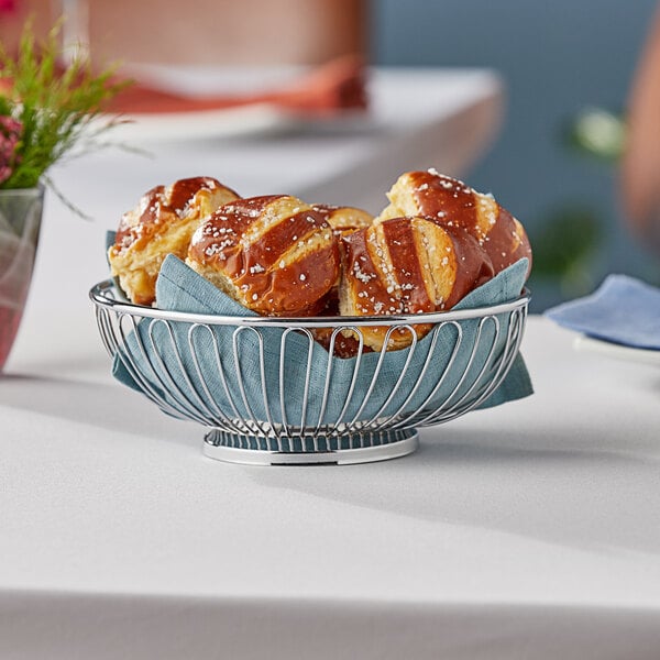 A Tablecraft small oval chrome basket filled with pretzels on a table.