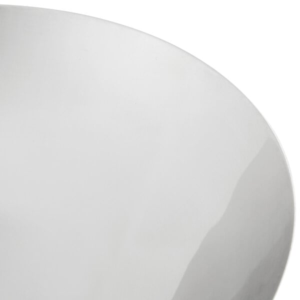 A stainless steel wok cover with a curved edge on a white surface.