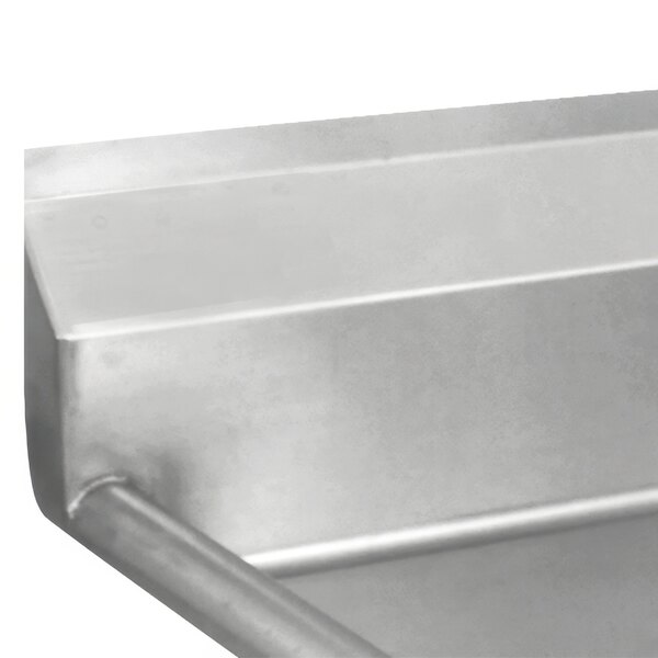 A stainless steel Advance Tabco three compartment sink with two drainboards on a metal surface.