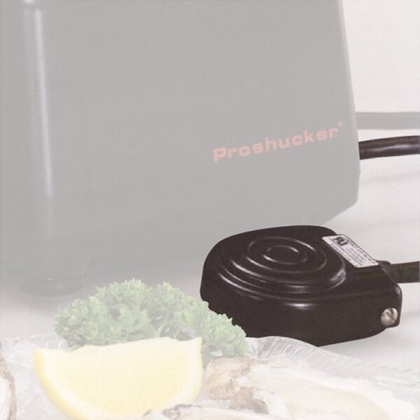A black foot pedal with a coiled design is shown next to a plate with lemon wedges and parsley, with part of a machine labeled 'Proshucker' visible in the background.