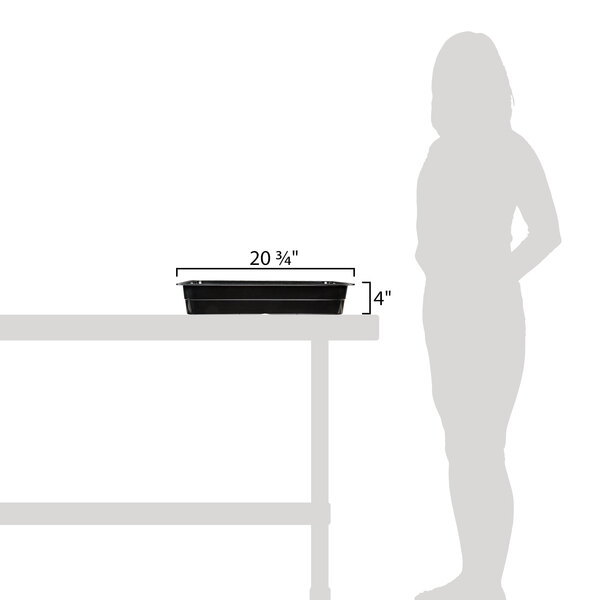 A woman using a GET black melamine food pan on a table in an outdoor catering setup.