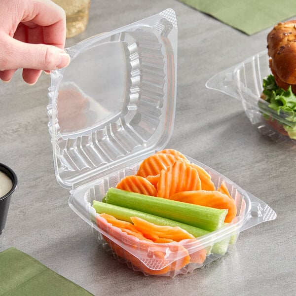 A clear plastic hinged lid container filled with sliced carrots and celery sticks.