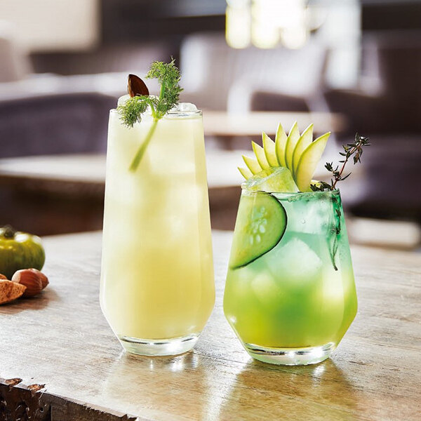Two Chef & Sommelier highball glasses with yellow and green drinks and cucumber garnish.
