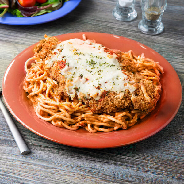 A plate of spaghetti and chicken with sauce on a GET Diamond Mardi Gras Rio Orange melamine plate.