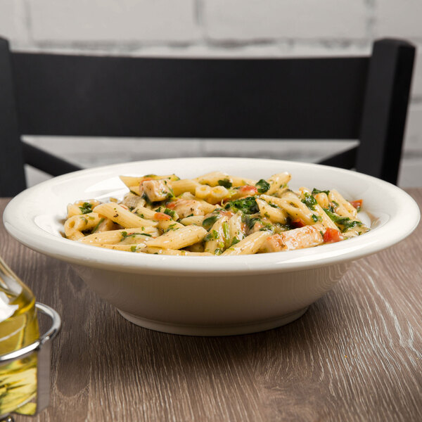 A Tuxton eggshell china pasta bowl filled with pasta on a table.