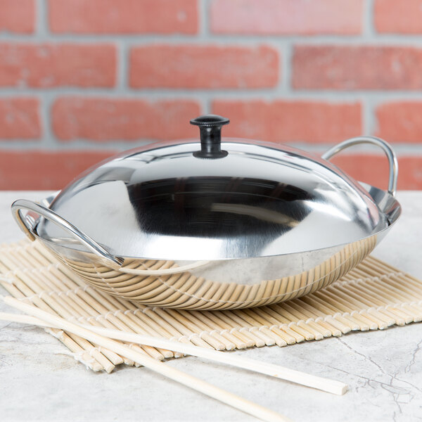 A silver Thunder Group stainless steel wok serving dish with a lid on a bamboo mat.