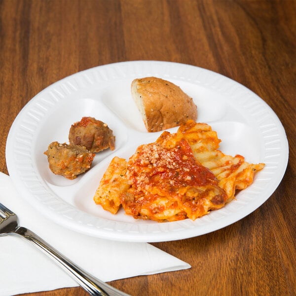 A Dart white foam plate with pasta and meat on it on a table.