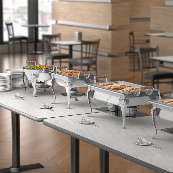 A buffet table with food in Choice Classic 4 Qt. Half Size Chafer dishes.