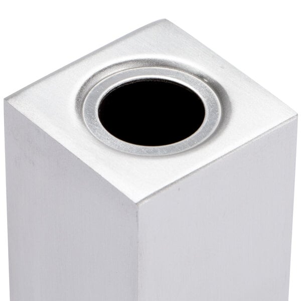 A close-up of a rectangular stainless steel metal container with a black hole in the center.