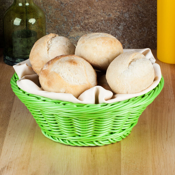 A green Designer Polyweave bread basket filled with bread on a table.