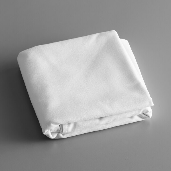 A folded Intedge white poly cotton blend tablecloth on a gray surface.