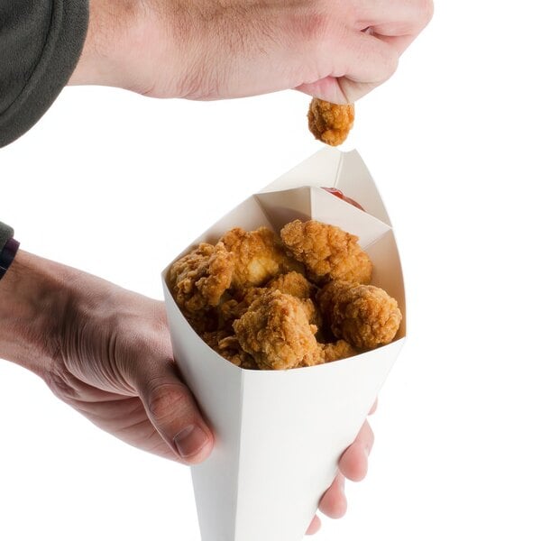 A person holding an American Metalcraft cardboard square fry cone filled with fried chicken.