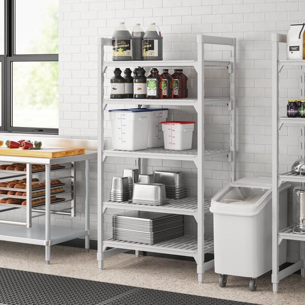 A Cambro Premium Camshelving unit in a professional kitchen with food containers on shelves.