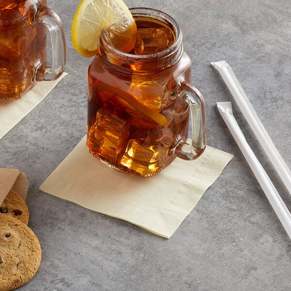 A glass mug with ice and a lemon slice on a table with a jar of lemon slices and a Choice ivory beverage napkin.