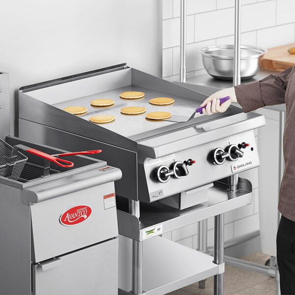 A man using a Garland natural gas countertop griddle on a counter in a professional kitchen.