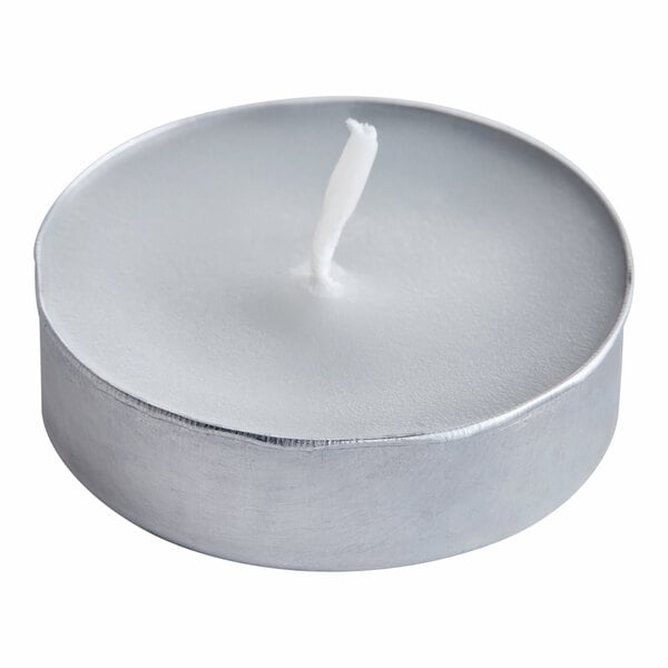A small white tea light candle in a round metal holder.