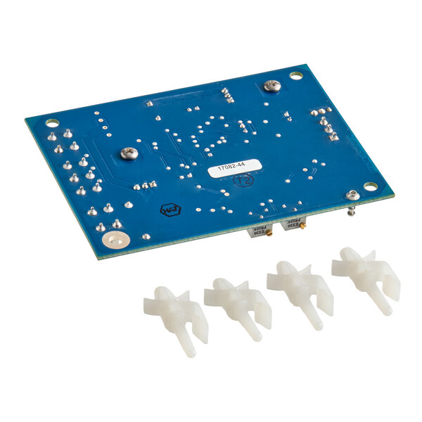 A blue printed circuit board with various solder points and four white plastic components placed in front of it.