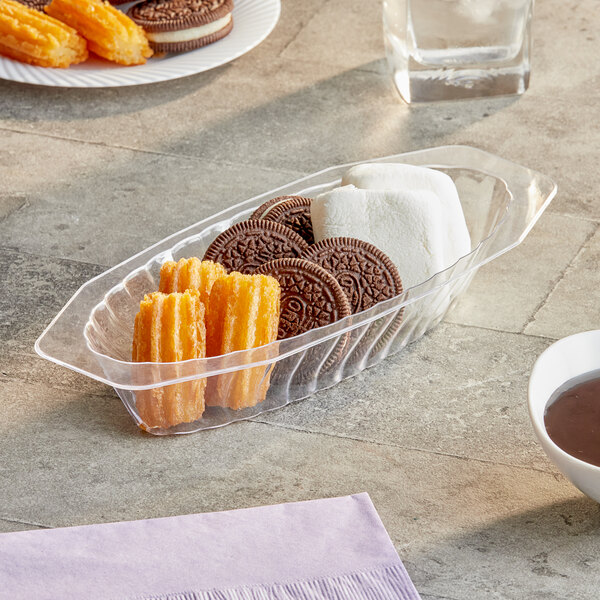 A Fineline Flairware clear plastic oval bowl filled with cookies, marshmallows, and chocolate on a table