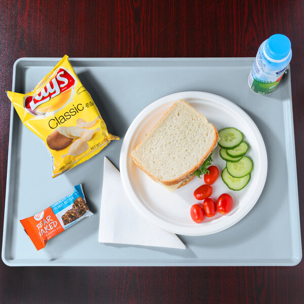 A plate of food with a sandwich, chips, and a drink on a Cambro sky blue dietary tray.
