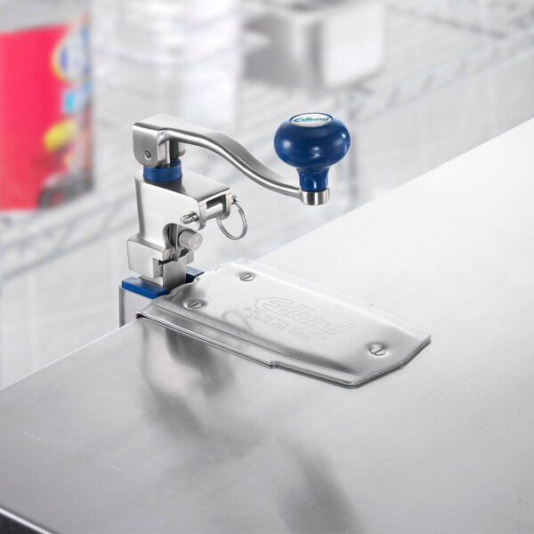 An Edlund commercial can opener with a stainless steel and blue metal handle on a table.