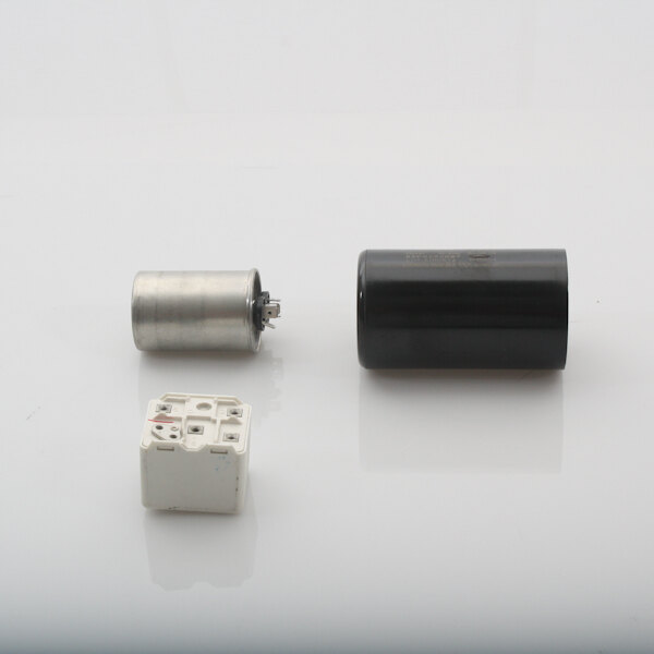 A black and silver SaniServ capacitor kit with a white square object with holes.