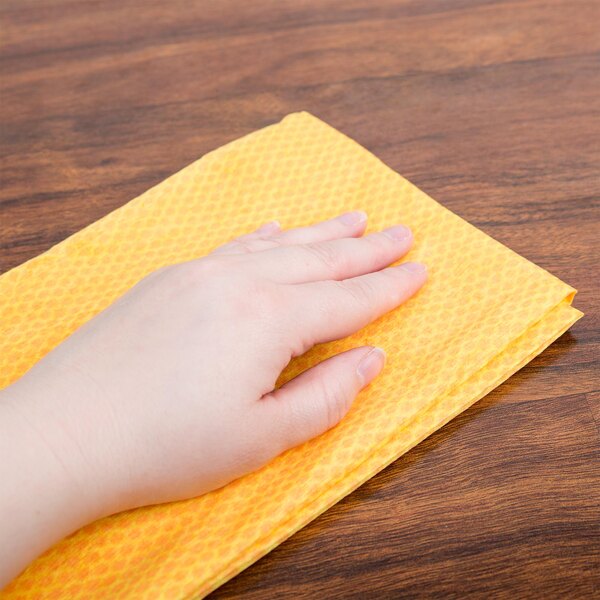 A person's hand using an orange Chicopee dusting cloth.