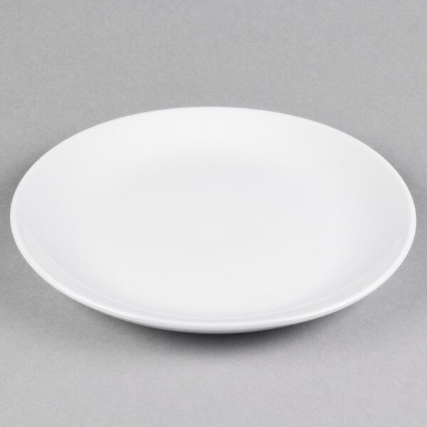 A white Tuxton healthcare plate with a white rim on a gray surface.