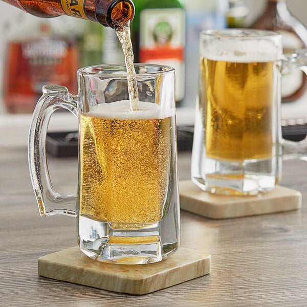 A person pouring beer into an Anchor Hocking Clarisse beer mug on a table.