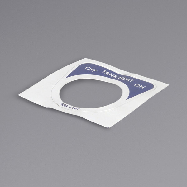A gray tank cover with a white and blue circular label with a hole in the middle.