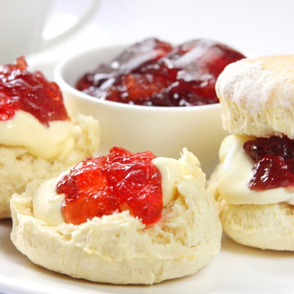 A plate of biscuits with grape, strawberry, and mixed fruit jelly cups.