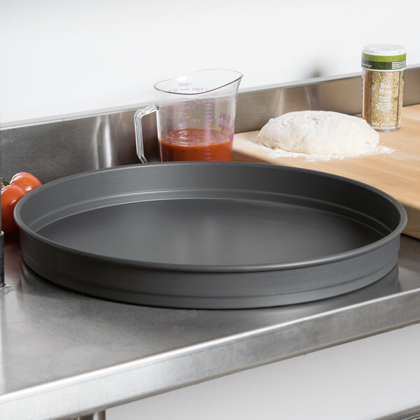 An American Metalcraft hard coat anodized aluminum pizza pan on a counter.