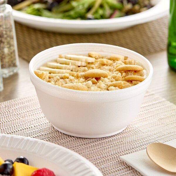A white Dart foam bowl filled with food on a table.