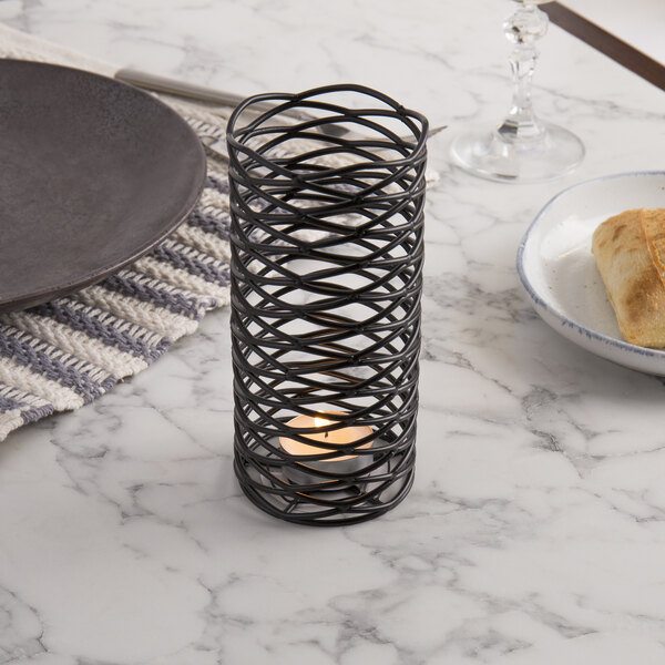 A black metal wire diamond candle holder on a table.