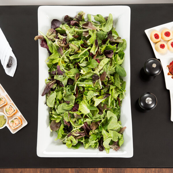 An American Metalcraft white stoneware platter holding a salad and other food on a table.