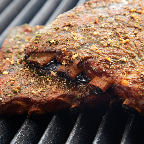 Two racks of ribs seasoned with Regal Big Flavor BBQ Seasoning cooking on a grill.