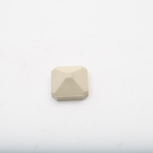 A white square stone with a triangular design on a white surface.