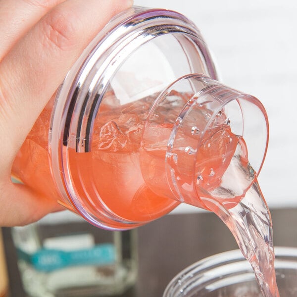 A hand pouring liquid into a Tablecraft Cobbler Cocktail Shaker.