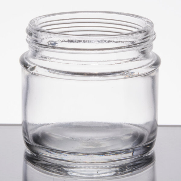 A Tablecraft clear glass tasting jar with a lid on a table.
