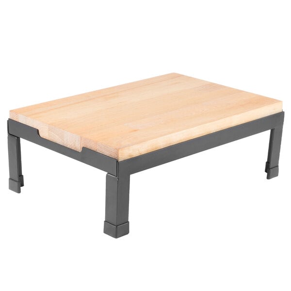 A Tablecraft butcher block riser with a black metal frame on a wooden table.