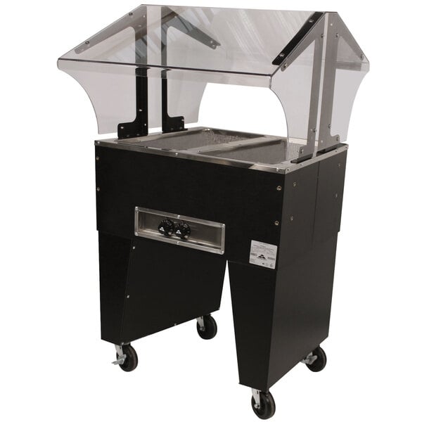 An Advance Tabco stainless steel hot food table with an open base and clear glass sneeze guard.