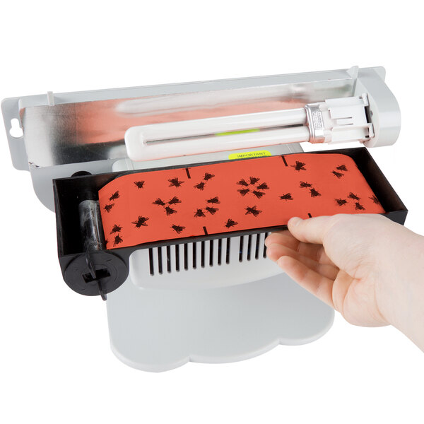 A hand inserting a red and black Paraclipse Fruit Fly Patrol cartridge into a machine.