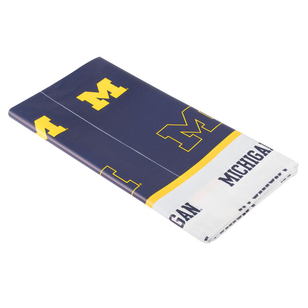 A white plastic table cover with blue and yellow University of Michigan logos.