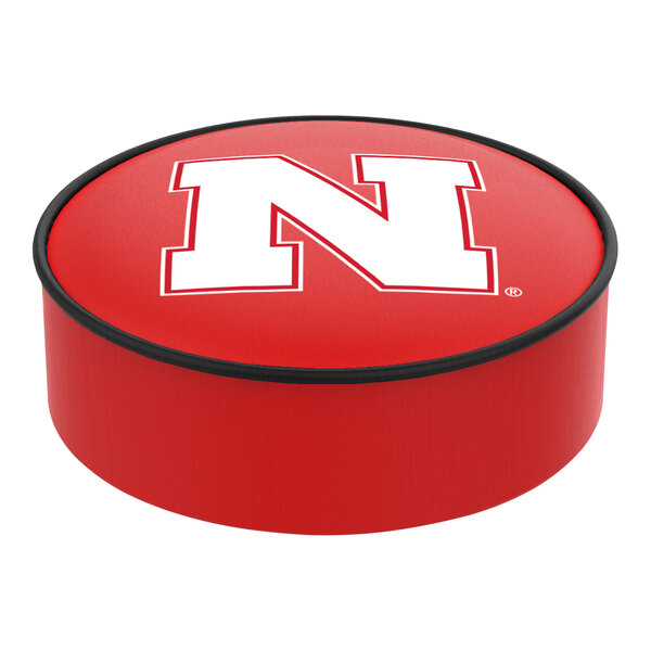 A red round vinyl bar stool seat cover with a white letter N and Nebraska logo.