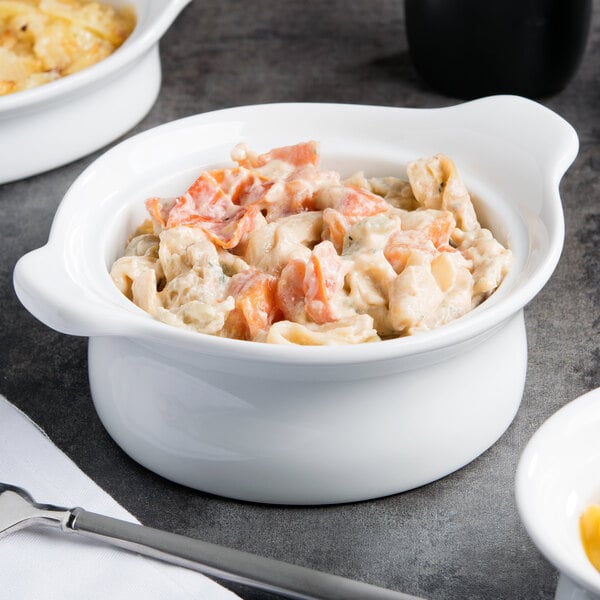 A white Libbey porcelain casserole dish filled with pasta and vegetables on a table.