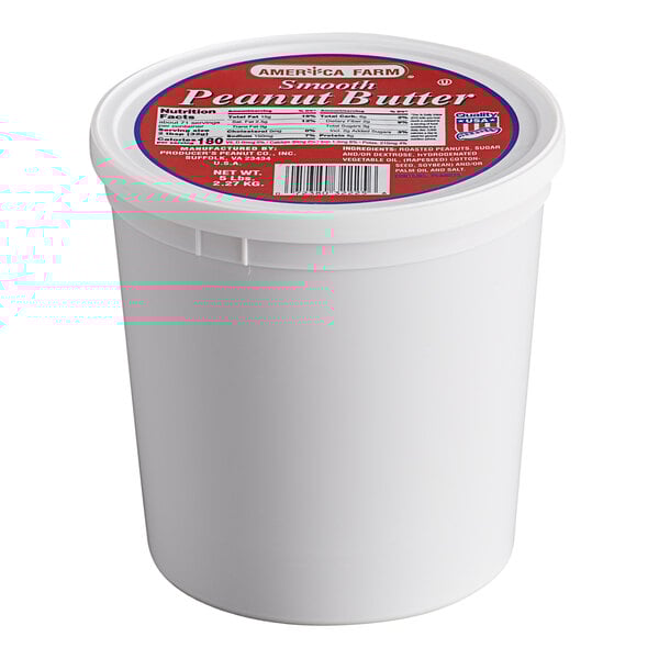 A white Producers Peanut Company container of creamy peanut butter with a red label.
