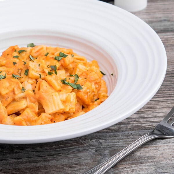 A white Elite Global Solutions melamine pasta bowl filled with pasta and a fork.