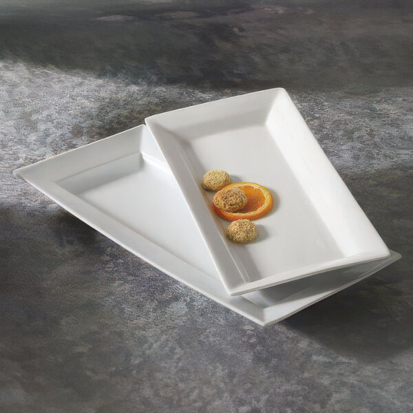 Two rectangular white CAC porcelain platters with food on them.