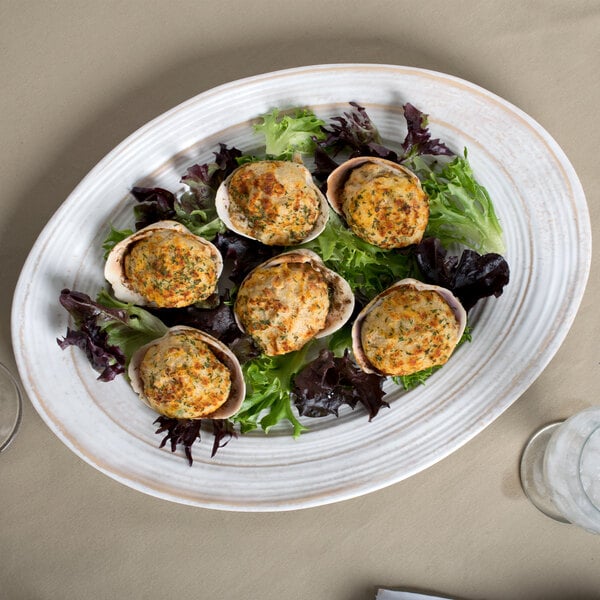An Elite Global Solutions Della Terra irregular oval serving dish with a plate of food on a table.