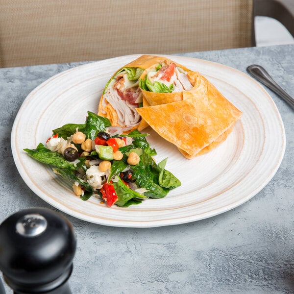 A plate with a tortilla wrap, sandwich, and salad on it.